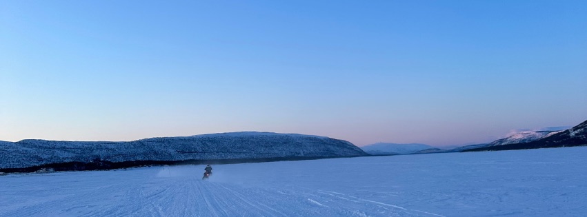 Snøscooter over frossen vidde i dus vinterkveld, Finnmark